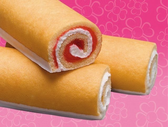 Two rolls of cake are stacked on top of each other on a pink background