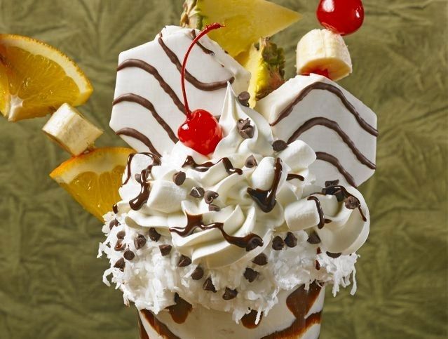 A milkshake with whipped cream and fruit on top