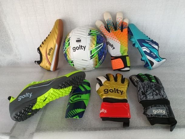 Guantes de portero de colores variados y balones de fútbol dispuestos sobre una superficie clara.