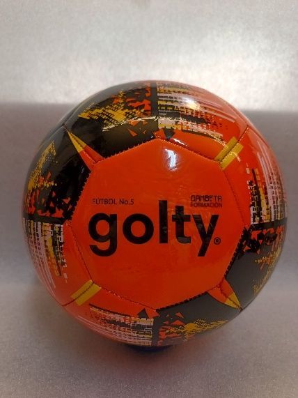 Balón de fútbol Golty naranja y negro sobre una superficie clara.