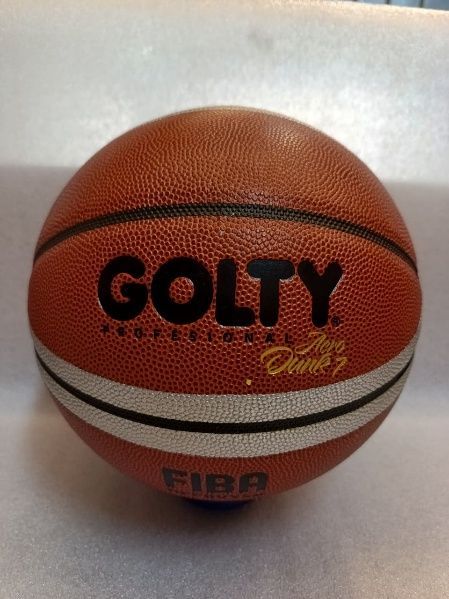Balón de baloncesto naranja con el logotipo “GOLTY” y rayas blancas sobre un fondo claro.