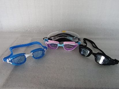Tres pares de gafas de sol dispuestas alrededor de un estuche amarillo sobre una superficie gris.