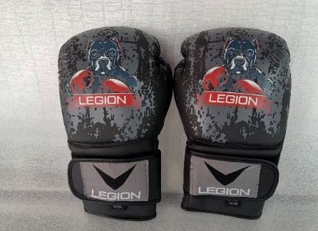 Un par de guantes de boxeo LEGION negros y rojos sobre un fondo gris.