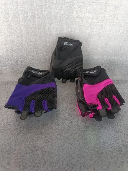 Tres pares de guantes de ciclismo sin dedos: morado, rosa y negro, sobre una superficie gris.