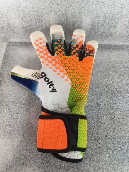 Guante de portero colorido con estampado naranja, verde y blanco sobre fondo gris.