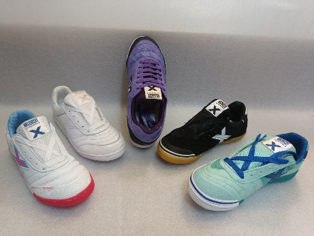 Cinco zapatillas de diferentes colores alineadas en un estante, incluyendo pares blancos, morados, negros y azul menta.
