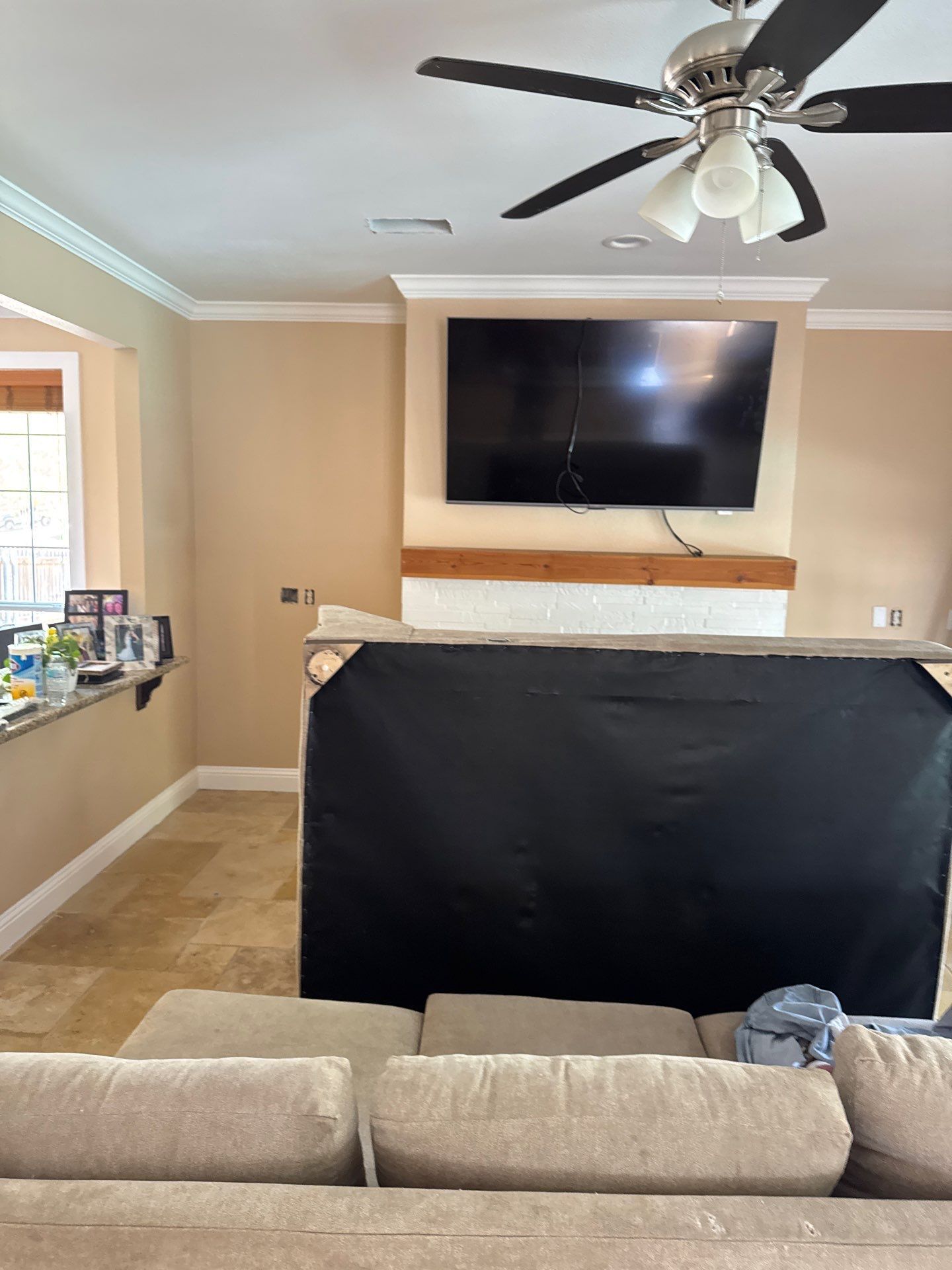 A living room with a couch , television and ceiling fan.