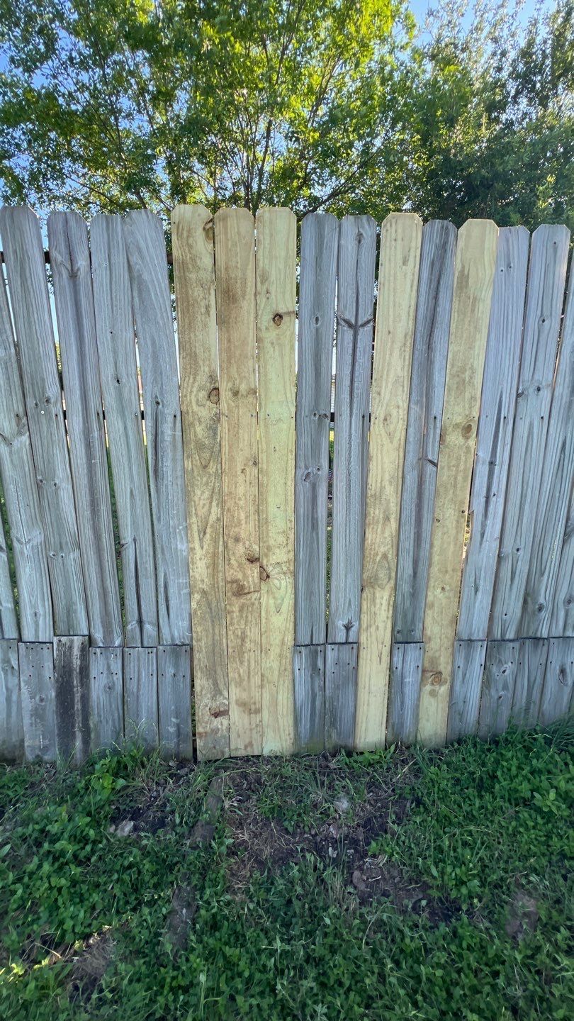 A wooden fence is sitting in the grass next to a tree.