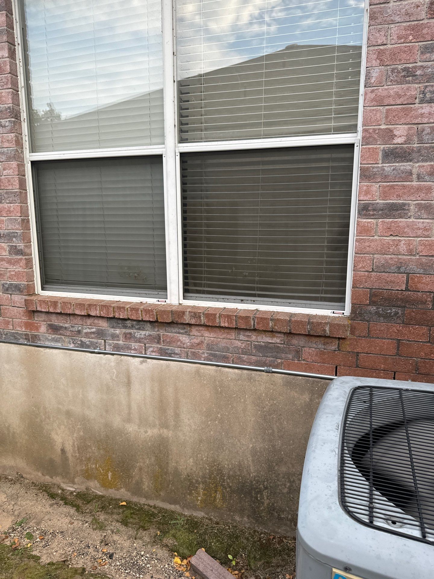 A brick house with a window and an air conditioner on the side of it.