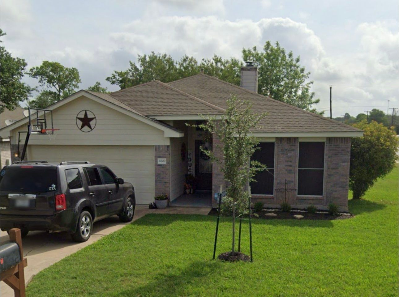 A car is parked in front of a house with a texas star on the roof