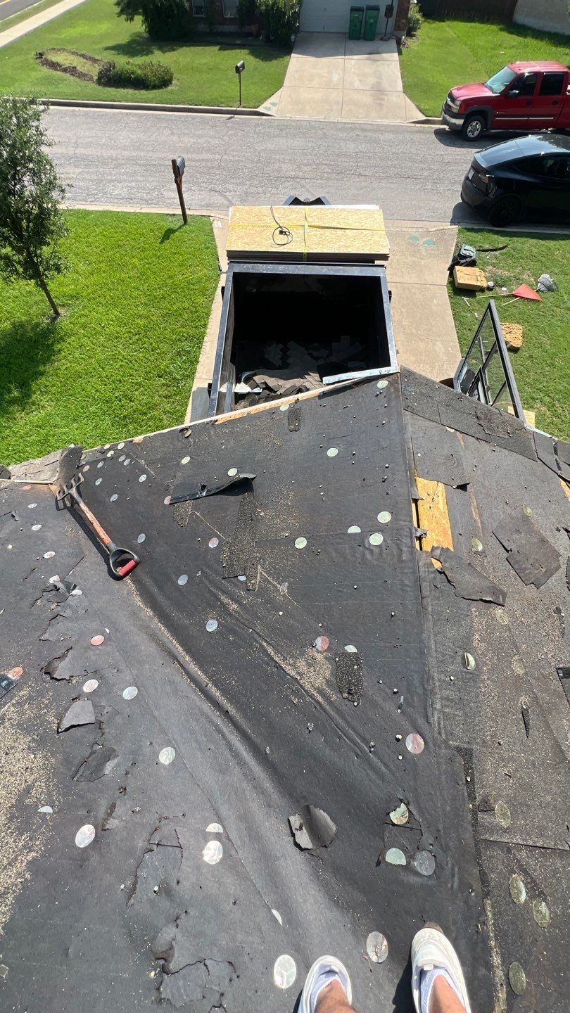 A person is standing on top of a roof with a truck in the background.