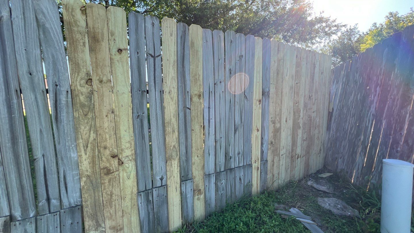 A wooden fence is sitting in the grass next to a white pipe.