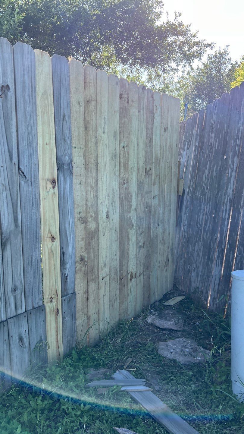 A wooden fence is being built in a backyard.