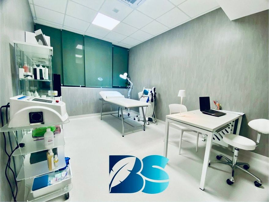 Corridoio di uno studio medico con sedie rosse, poster e pavimento a scacchi.