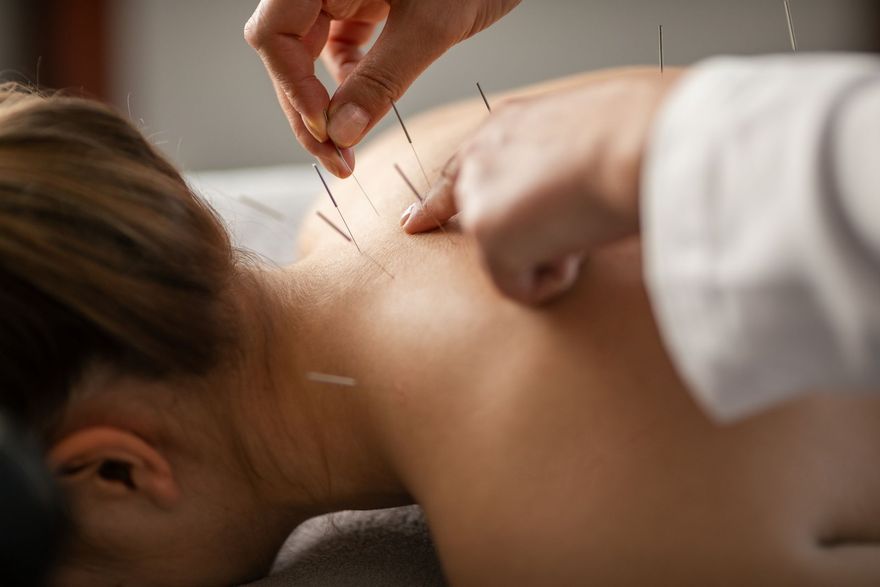 Corridoio di uno studio medico con sedie rosse, poster e pavimento a scacchi.