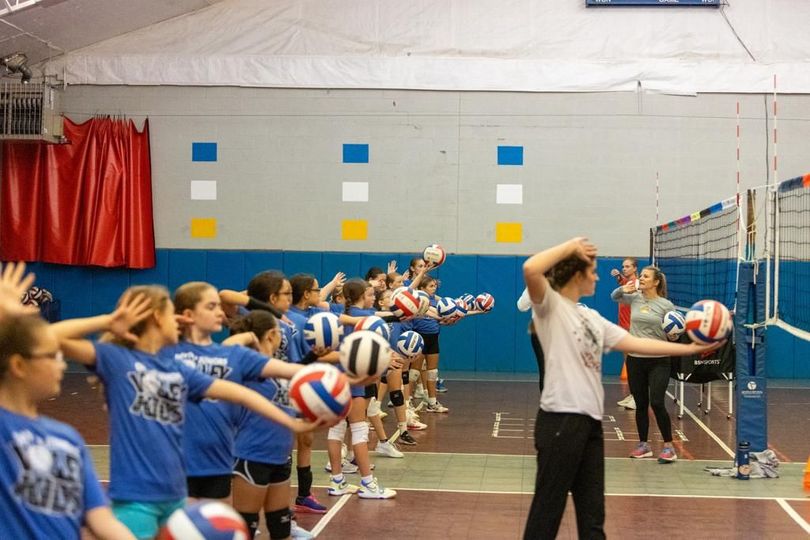 young volleyball players holding balls in gym