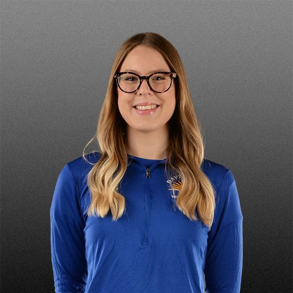 Portrait of a smiling person with glasses in a blue shirt against a gray background