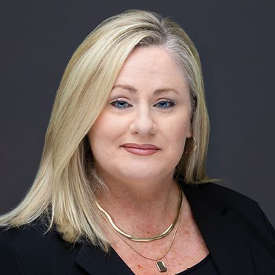 Portrait of a smiling blonde woman in a black top against a dark gray background