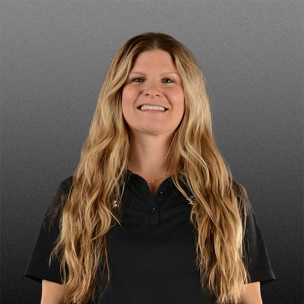 Smiling person with long blonde hair wearing a black shirt against a gray background