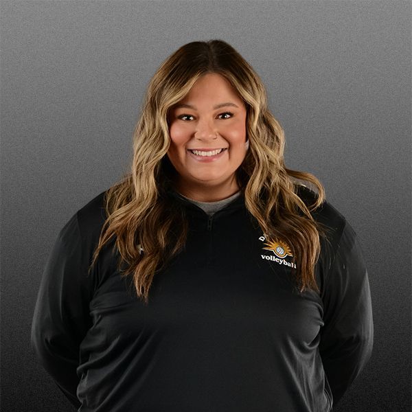 Smiling person in a black logo sweatshirt against a gray backdrop