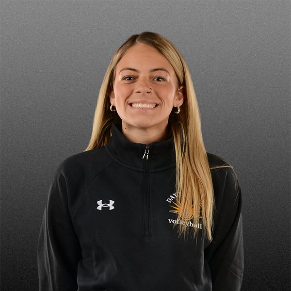 Smiling person in a black zip-up jacket on a gray background