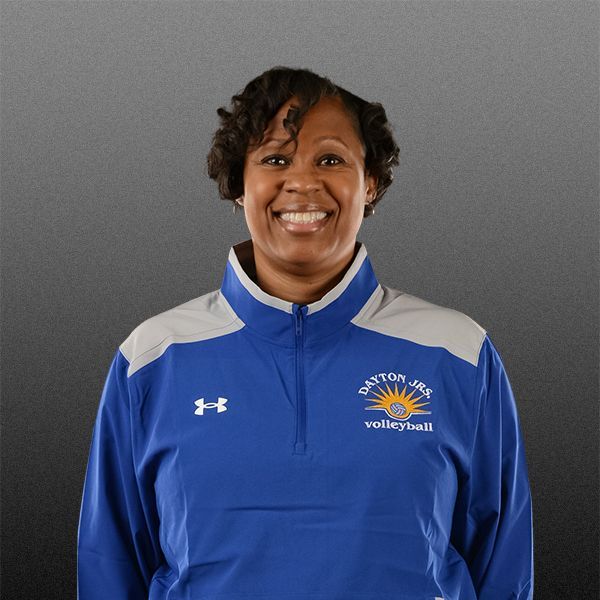 Smiling volleyball coach in a blue Under Armour pullover against a gray background