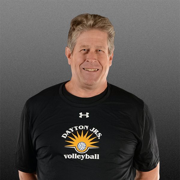 Man smiling in black T-shirt against a gray background