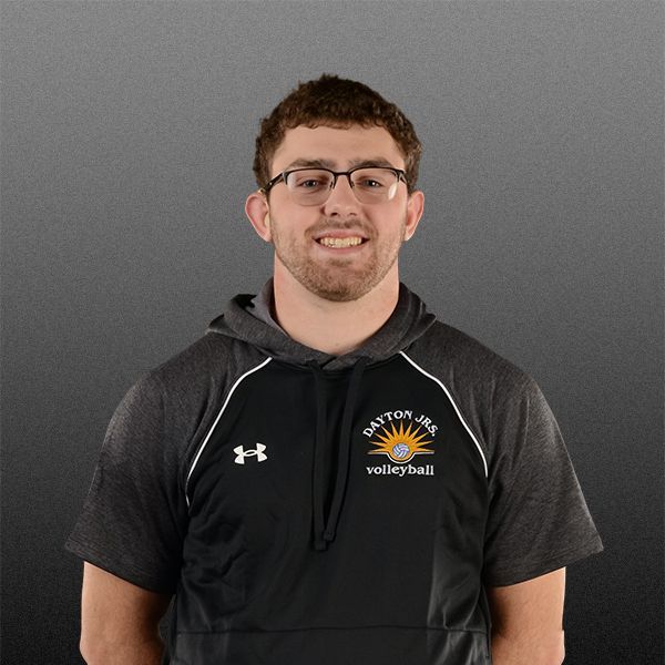 Portrait of a smiling person in a black hoodie against a gray background