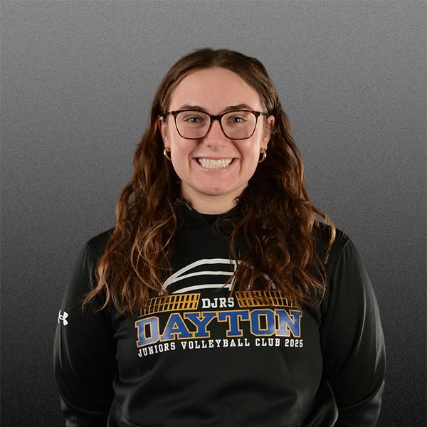 Smiling person in glasses and black Dayton volleyball hoodie against a gray background
