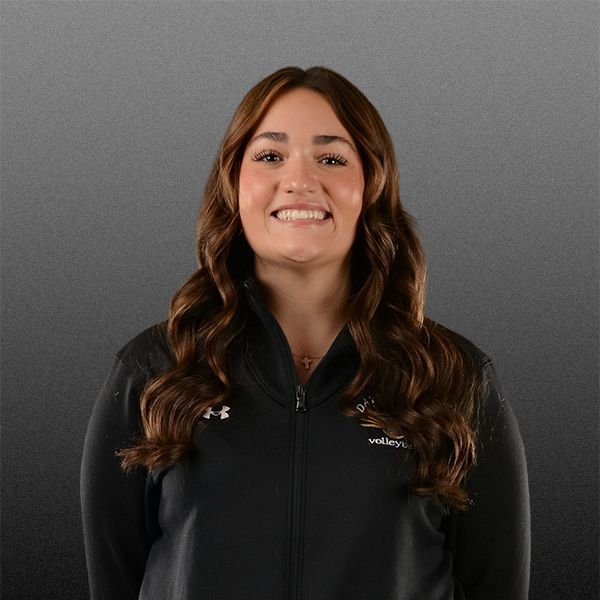 Woman smiling in a black zip-up jacket against a gray background