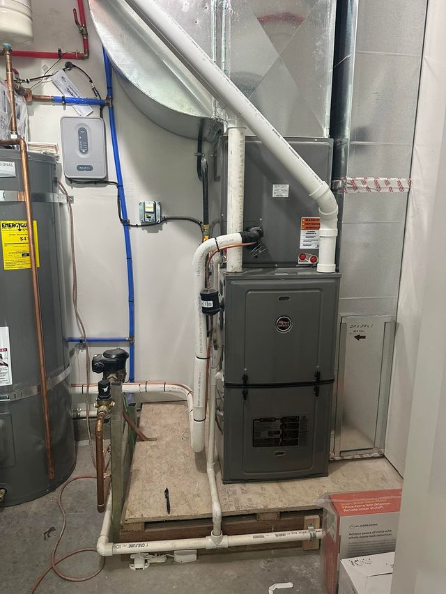 A room with a furnace , water heater , and pipes.