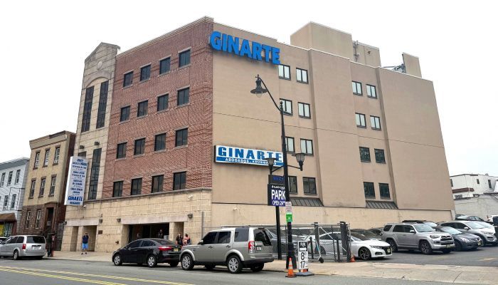 Exterior view of the Ginari's building with a brick facade, street parking, and parked cars.