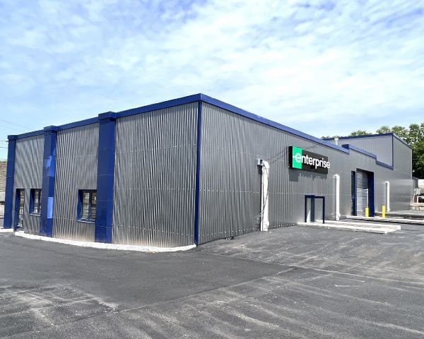 Enterprise car rental facility with a gray corrugated metal exterior and blue trim.