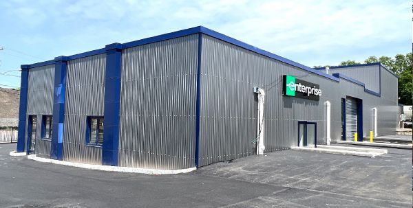 Enterprise car rental facility with a gray corrugated metal exterior and blue trim.