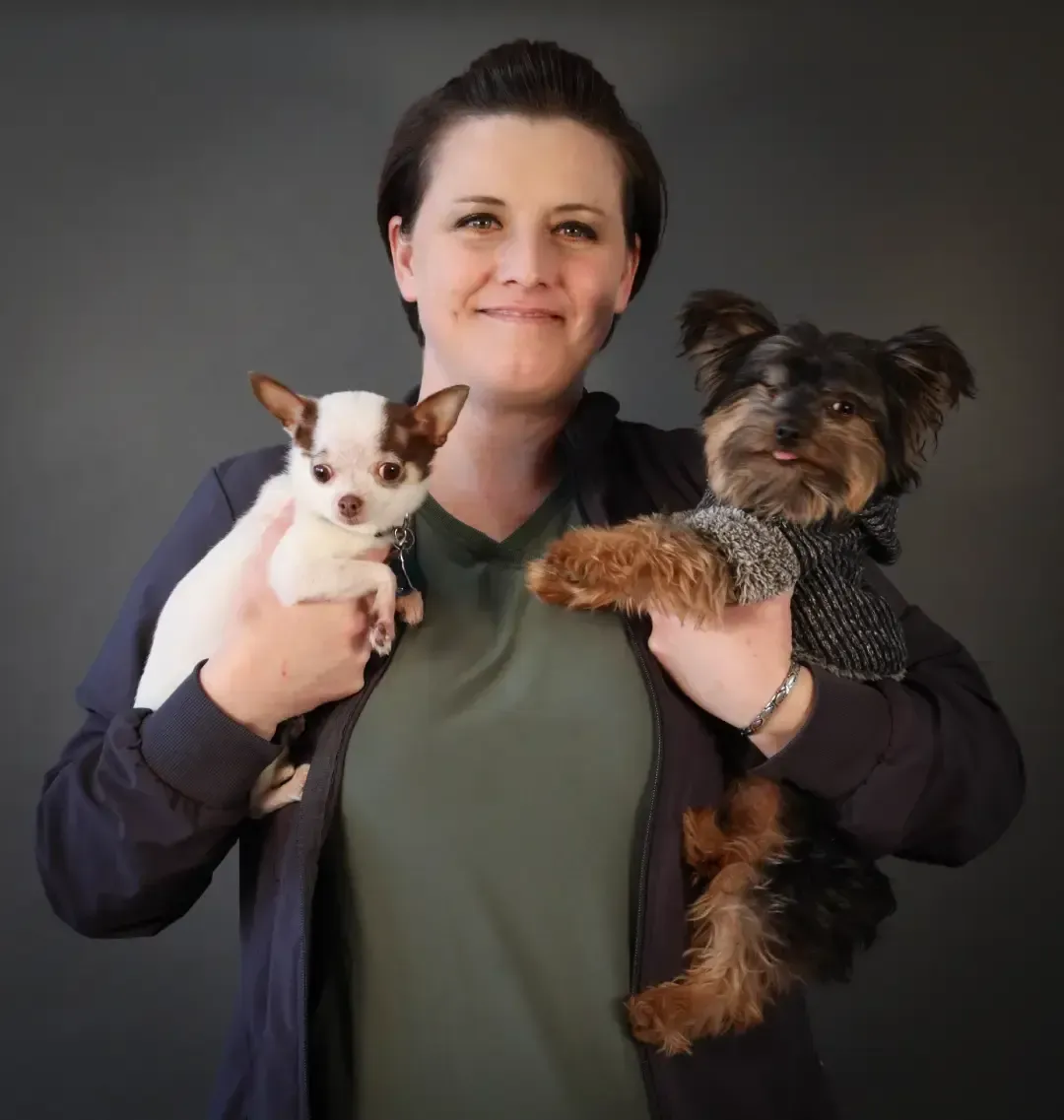 Woman holding two small dogs against a dark background