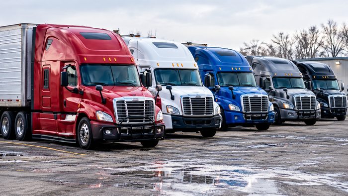 Row of red, white, and blue semi trucks parked on a wet lot