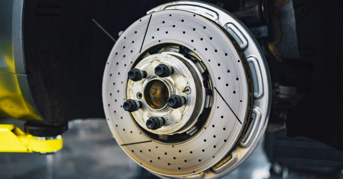 Primer plano del disco de freno perforado y el cubo de la rueda de un coche en un garaje.