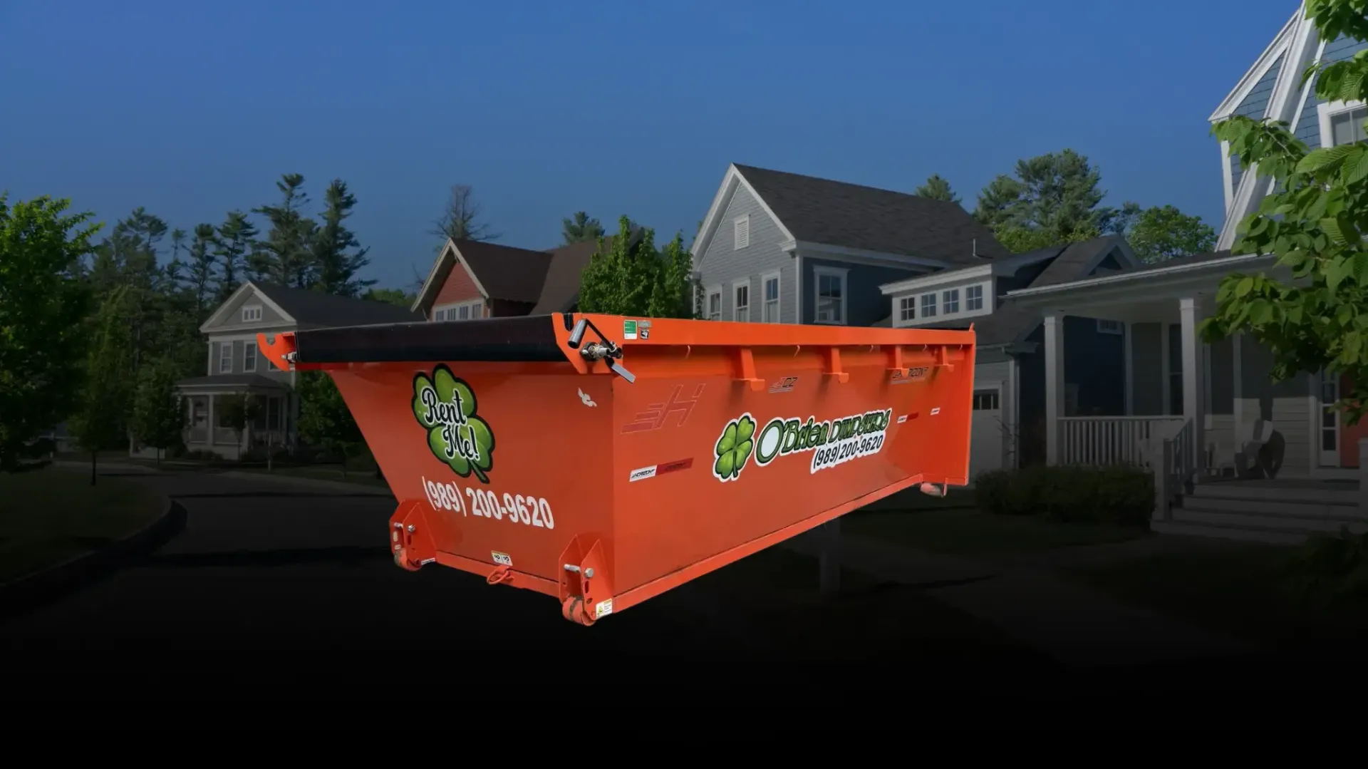 Orange construction dumpster in front of suburban houses on a sunny street