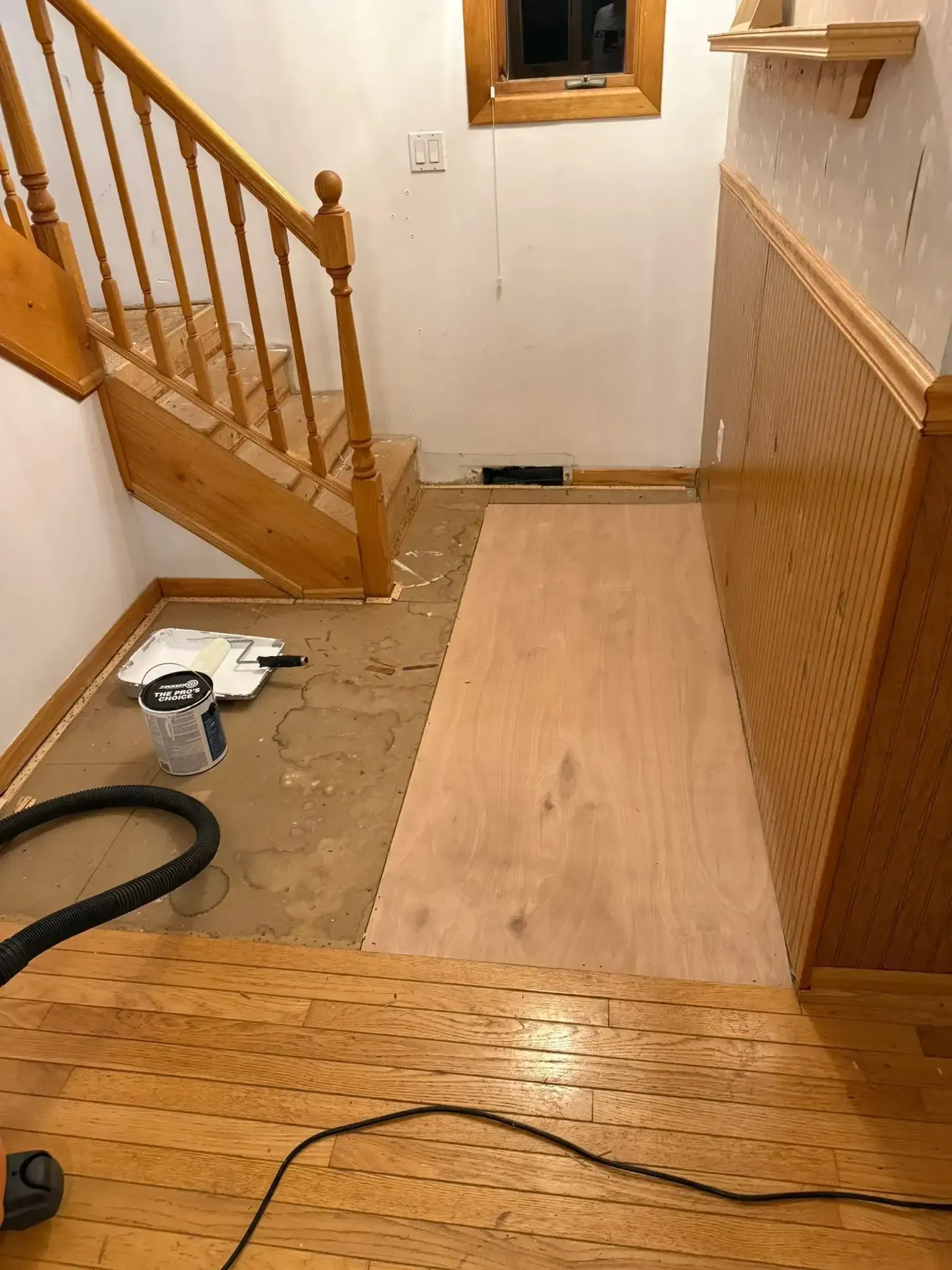Renovated stair landing with exposed floorboards, wooden stairs, and a small window