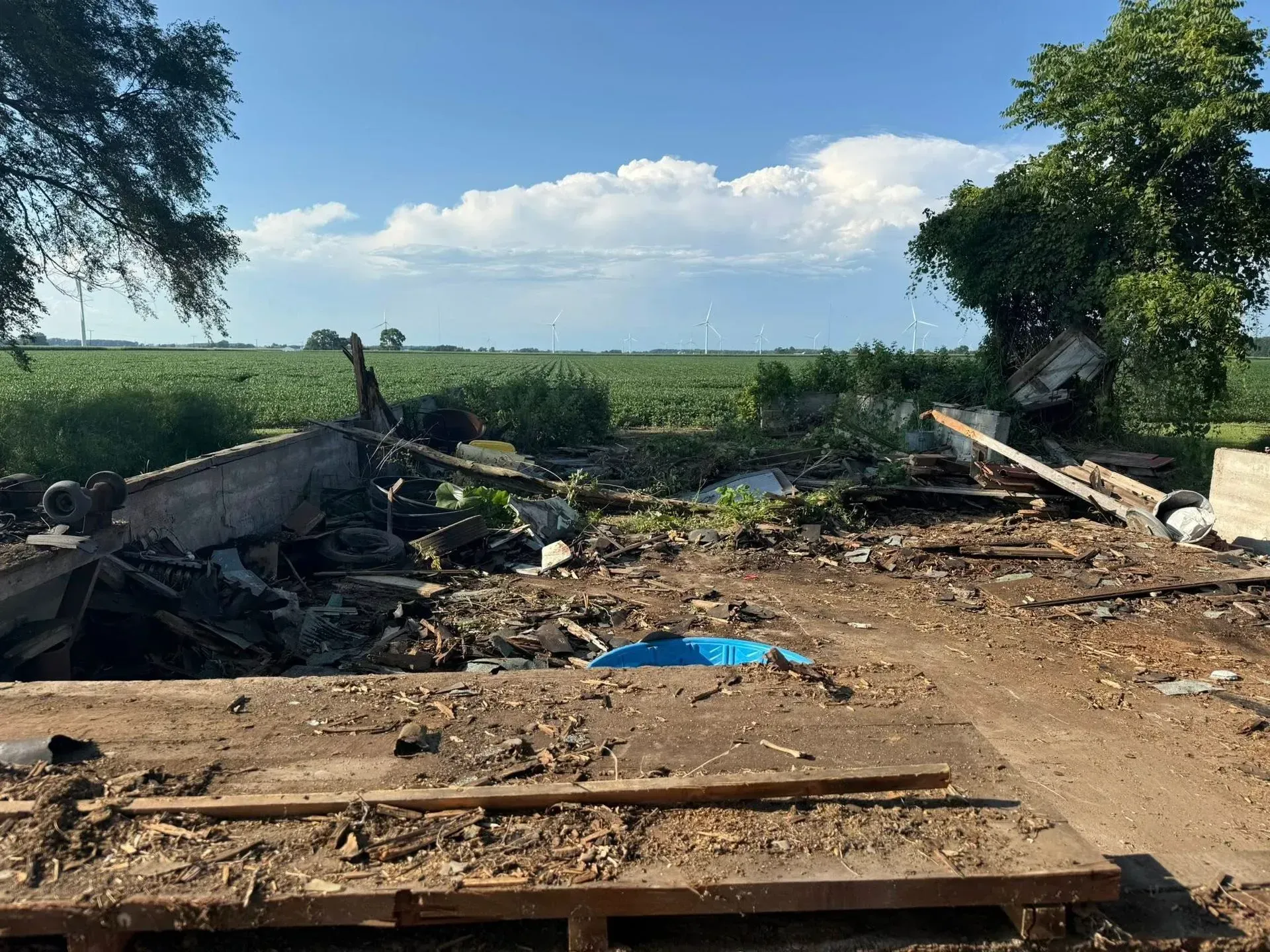 Burned debris and charred remains in a rural field under a blue sky