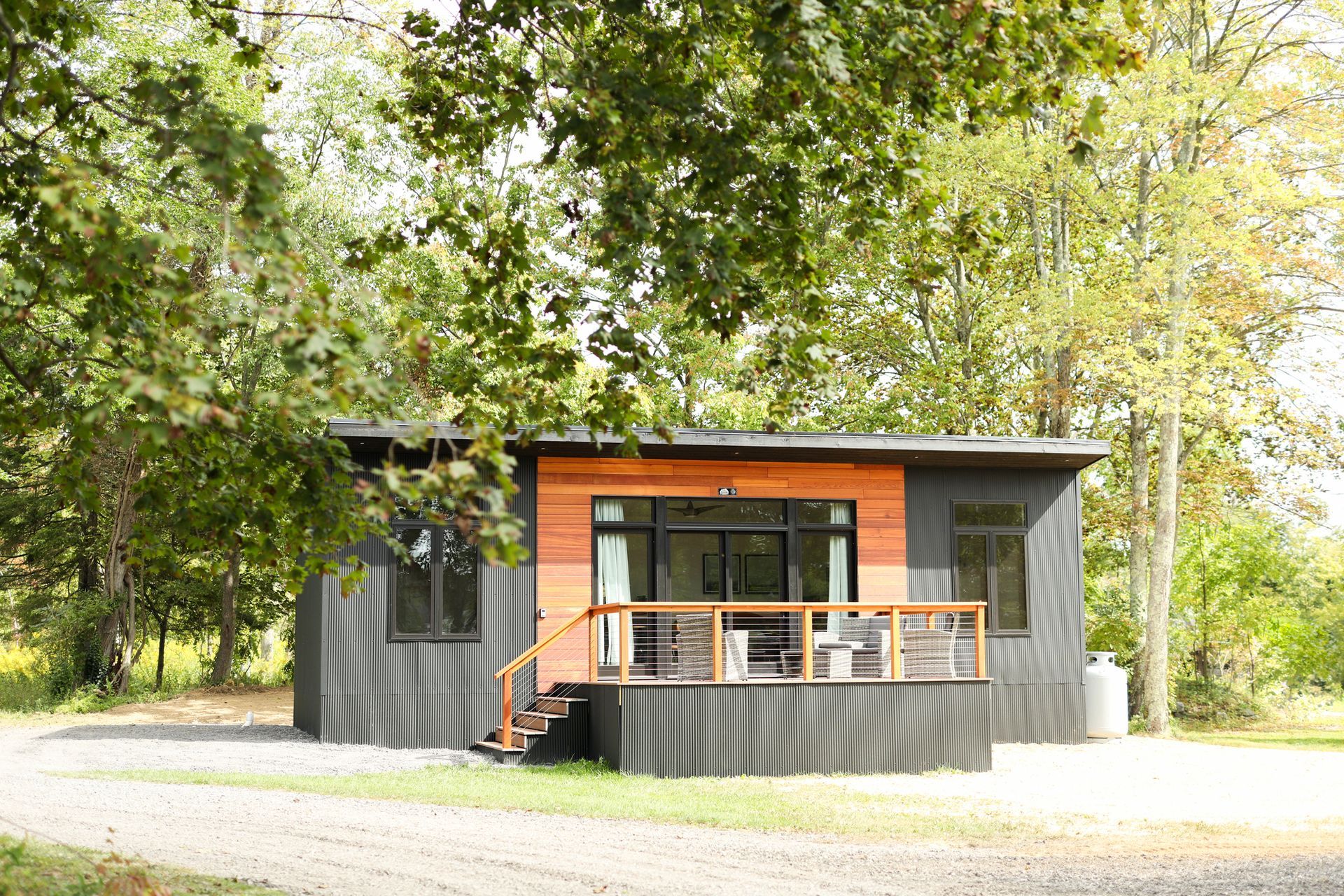 A small house with a large deck is surrounded by trees.