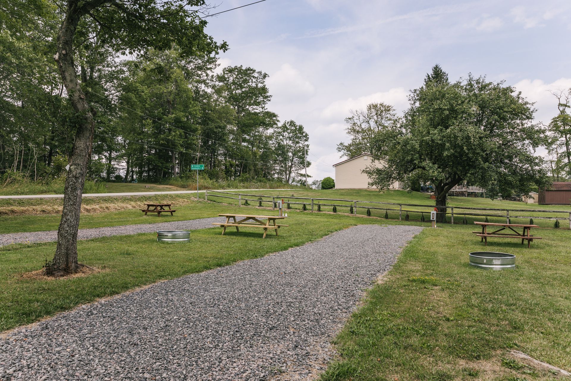 A welcome to greene hills camp sign is in the middle of a grassy field.
