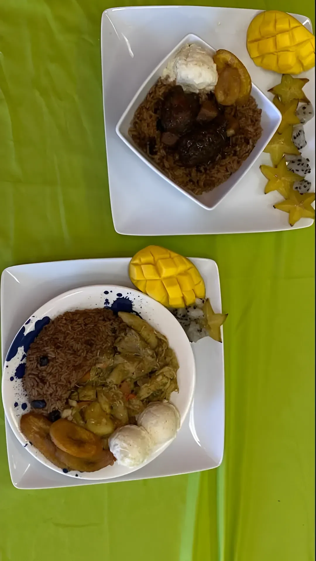 Two takeout containers of rice and curry on a green table, with sliced mango and dessert beside them