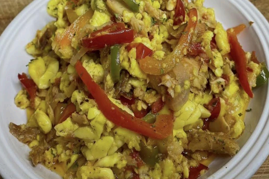 Scrambled eggs with red pepper strips and herbs on a white plate