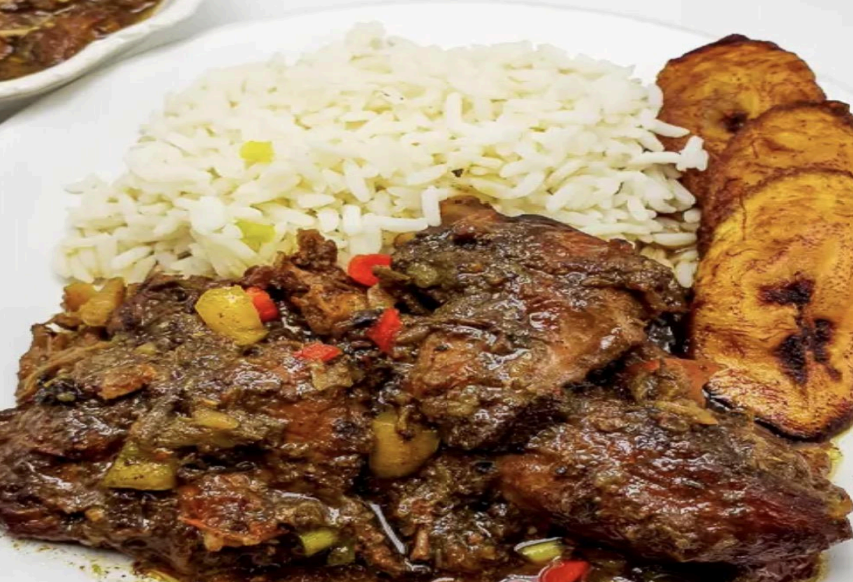 Plate of rice with dark sauced meat and fried plantains on the side