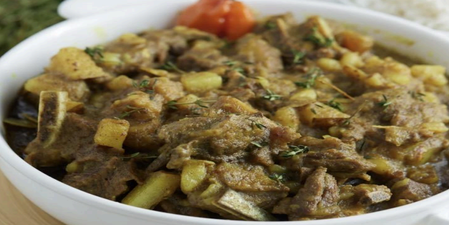 Bowl of hearty stew with chunks of meat, potatoes, and herbs in a light broth