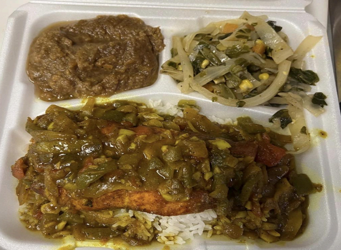Takeout meal with rice, curry, and sautéed vegetables in a foam container