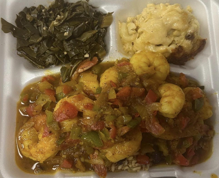 Foil takeout tray with greens, mashed potatoes, and shrimp stew topped with peppers and sauce