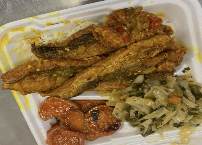 Takeout container with fried fish, sautéed vegetables, and tomato-based side dish