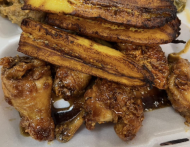 Plate of fried chicken wings topped with plantains